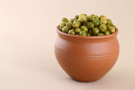 Spiced fried green peas {chatpata matar} Indian snack. Dried salted green peas in clay pot.の写真素材