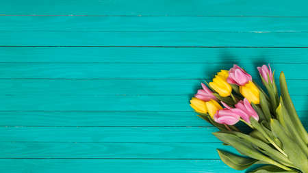 top view yellow pink tulip flowers green wooden deskの写真素材