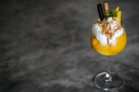 mango and passion fruit tropical ice cream sundae in glassの写真素材
