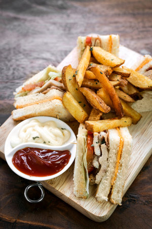 classic club sandwich with fries on wooden board