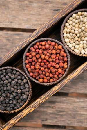 Organic white red and black pepper corns in wood displayの写真素材