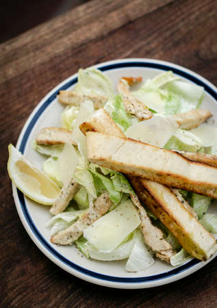 simple healthy chicken caesar salad on wood tableの写真素材