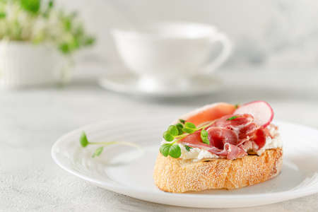 Mediterranean appetizer. Open sandwich with prosciutto or jamon on white plate. Copy spaceの写真素材
