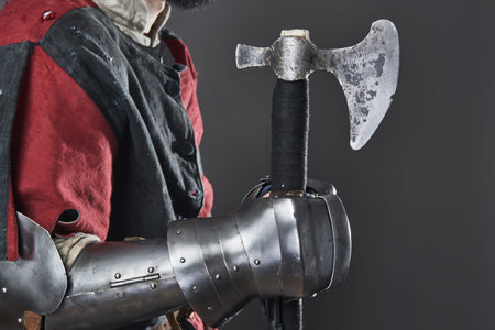 Medieval knight on grey background. Portrait of brutal dirty face warrior with chain mail armour red...