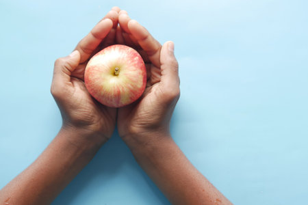 child boy hand hold a apple on blue background .の写真素材