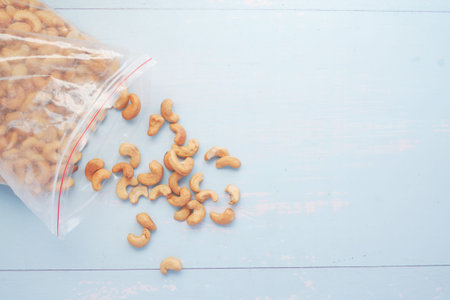 cashew nut spilling from a plastic bag on table ,
