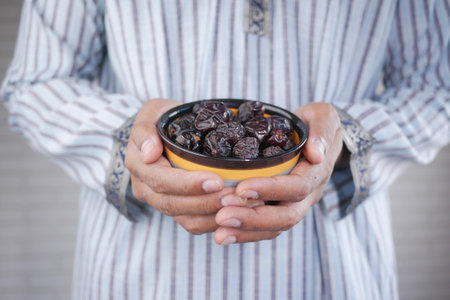 the concept of ramadan, hand holding a bowl of date fruits .