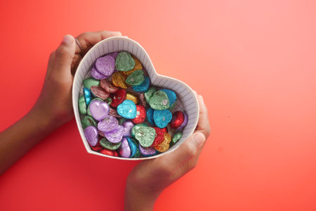 small heart shape gift with candy on red background