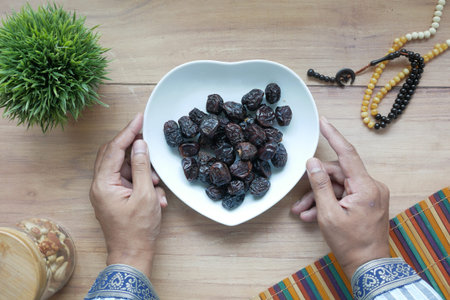 the concept of ramadan, hand holding a bowl of date fruits .