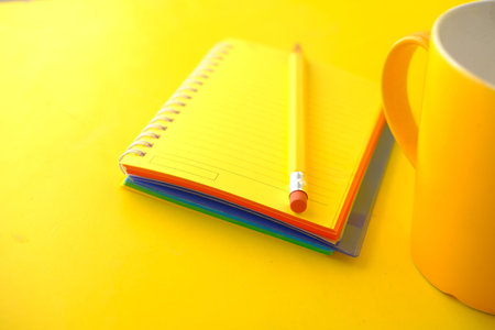 yellow color notepad with pencil on yellow desk .