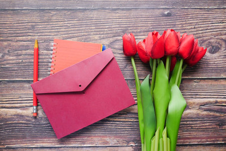 envelope and red tulip on table .
