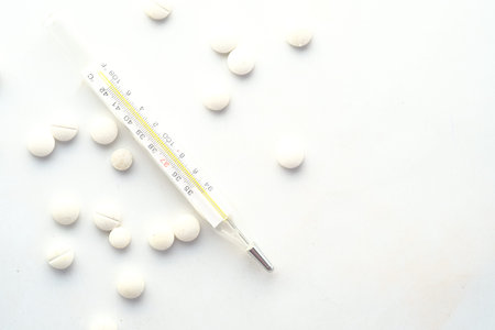 medical thermometer and pills on white texture background.