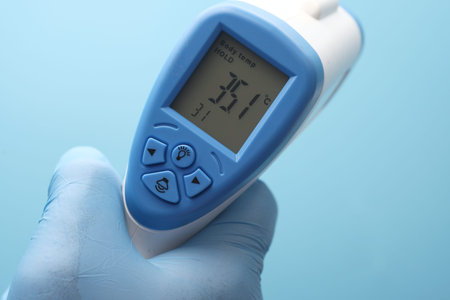 Hand holding infrared thermometer to measuring temperature