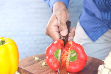 cutting red capsicum on chopping background .