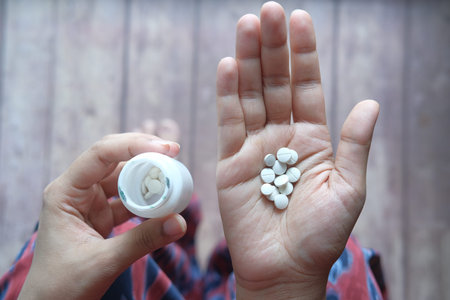 Close up of women hand taking pills.