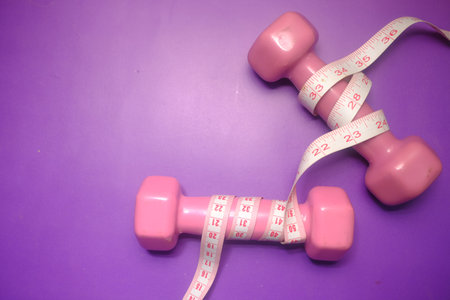 Fitness concept with dumbbell and measurement tape on purple background ,の写真素材