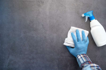 hand in blue rubber gloves cleaning table with clothの写真素材