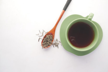 top view of green tea and herbal leaf in a small glass bowl on table .