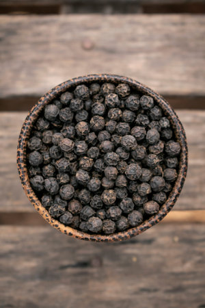 organic kampot dried black pepper corns in traditional wood bowl in cambodia