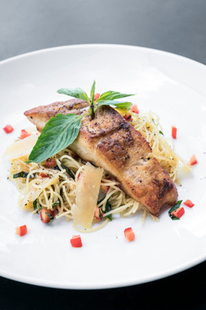 fresh cod fish fillet on mixed vegetable and parmesan spaghetti pasta