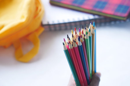 child girl holding many color pencils .