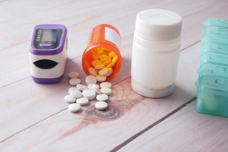 pulse oximeter, medical pills and container on table .
