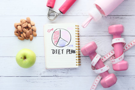 Diet plan with apple and dumbbell on pink background .の写真素材