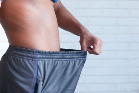 the concept of weight loss, young man pulling pant .