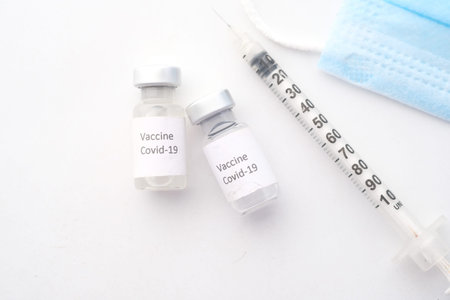 Close up of coronavirus vaccine and syringe on white background.