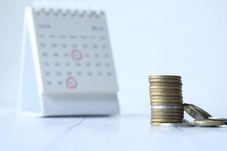 deadline concept with stack of coins and calendar on white background ,の写真素材
