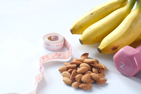 Diet plan with almond nut, dumbbells, banana on table.の写真素材