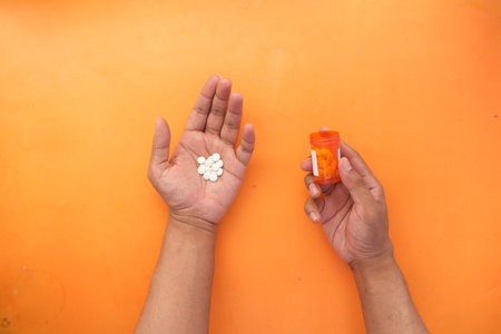 man's hand with pills spilled out of the container .の写真素材