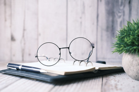 notepad, eyeglass and a pencil on wooden table .の写真素材