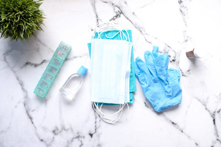 Surgical masks, gloves, sanitizer and pills on tiles background .
