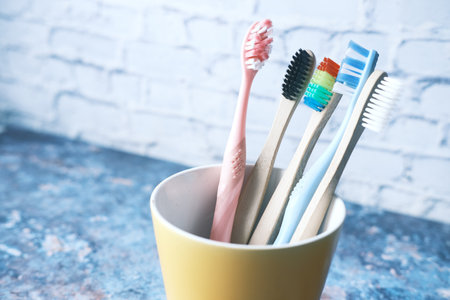 colorful toothbrushes in white mug against a wall .の写真素材