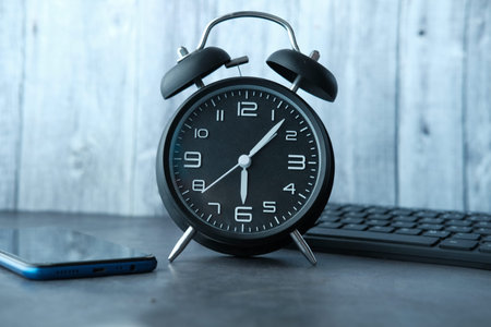 smart phone , keyboard and alarm clock on table .