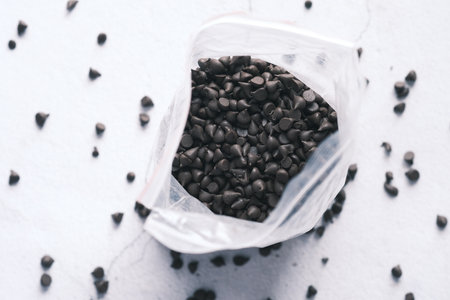 Chocolate chips spilling from a plastic packetの写真素材
