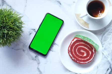 top view of smart phone, tea and a cake on tiles background ,の写真素材
