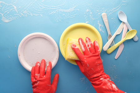 man in protective rubber gloves holding a sponge cleaning colorful plate .の写真素材