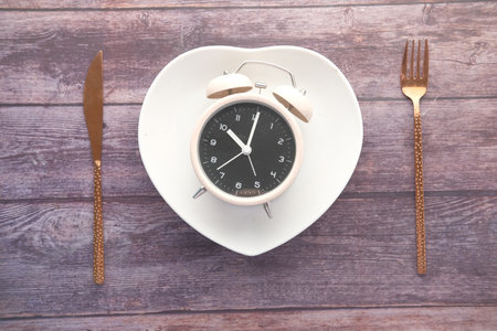 Alarm clock on plate on wooden table, top viewの写真素材