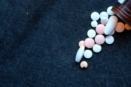 close up of white pills spilling on black background .の写真素材