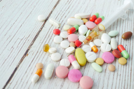 syringe and pills on dark background, close up.