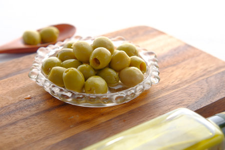 bottle of olive oil and fresh olive in a container on tableの写真素材