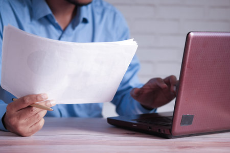 man hand with pen analyzing bar chart on paper.