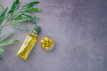bottle of olive oil and fresh olive in a container on black backgroundの写真素材