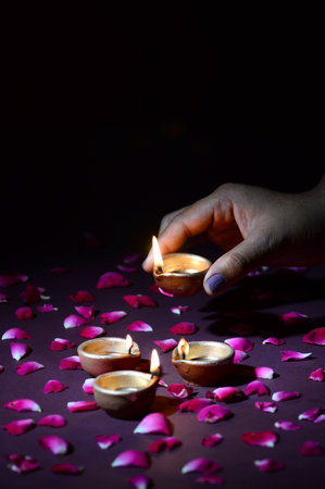 Hand holding and arranging lantern (Diya) during Diwali Festival of Lightsの写真素材
