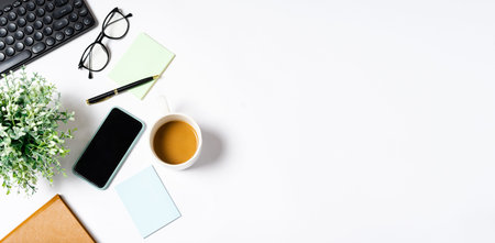 Top view of coffee, book, notebook, pen, keyboard, phone on white background