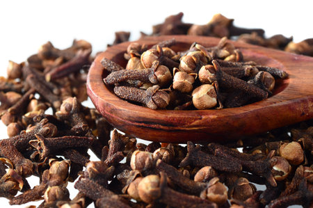 Cloves (spice) and wooden spoon close-up food background. Isolated on white backgroundの写真素材