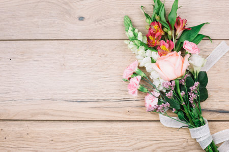 elevated view colorful flower bouquet tied with white ribbon wooden deskの写真素材