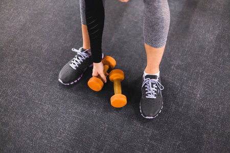 low section view woman picking dumbbell gymの写真素材